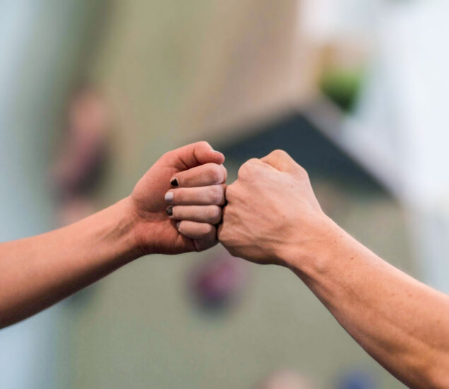 Two hands are shown giving a fist bump, symbolizing connection—one with black nail polish, the other without. The softly blurred background highlights unity, much like Access Memberships bring people together.
