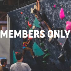 Two people climb a colorful indoor rock climbing wall while others watch. Large white text across the image reads MEMBERS ONLY. The setting appears to be a gym or climbing facility.