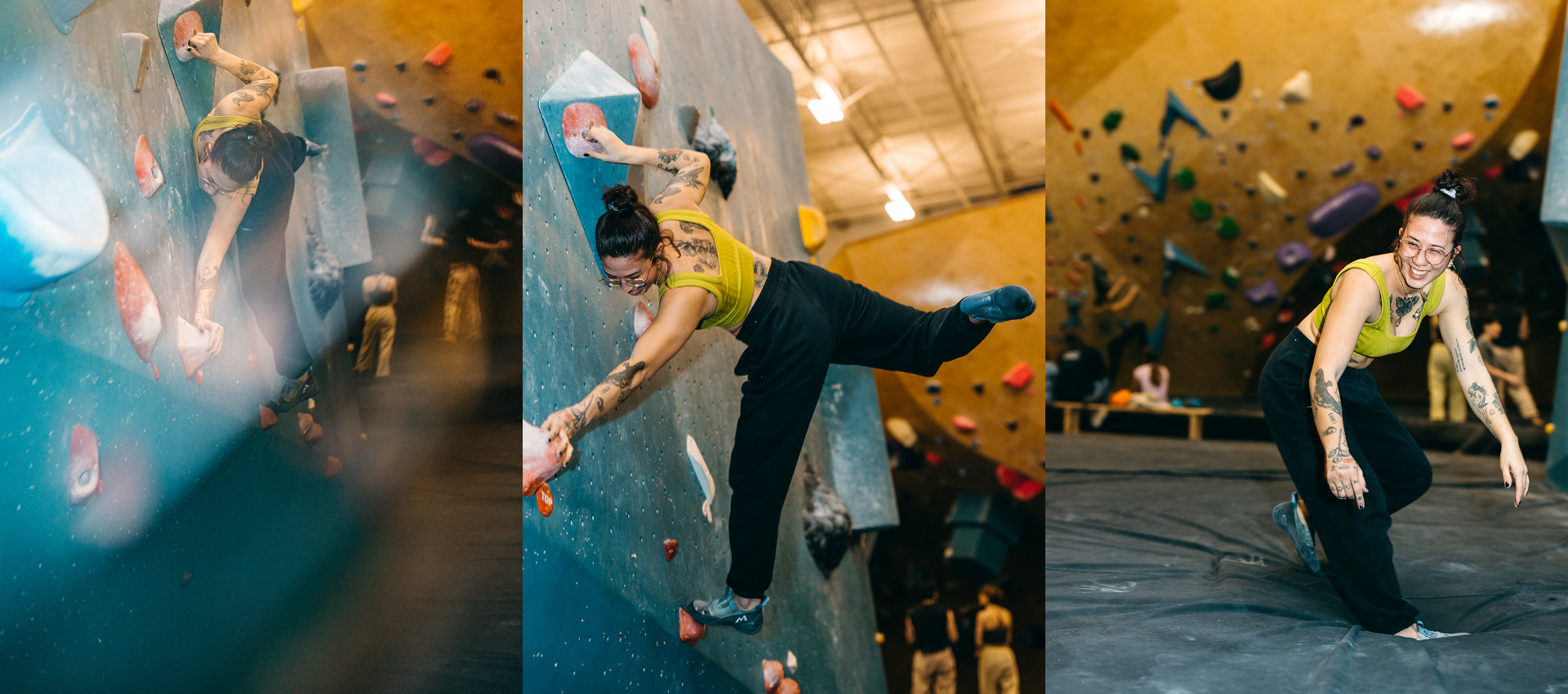 A woman with tattoos and glasses, wearing a yellow tank top and black pants, enjoys her climbing experience as she balances on an indoor bouldering wall at a climbing gym, then smiles and crouches on the mat after finishing her climb.