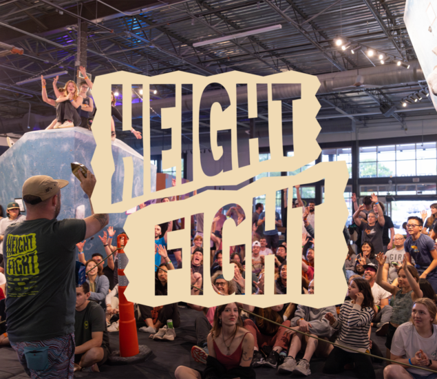 A crowd cheers and raises their hands at an indoor rock climbing event, part of Community & Events at Austin Bouldering Project. A person in the foreground wears a “Height Fight” shirt beneath bold, overlaid “HEIGHT FIGHT” text across the image.